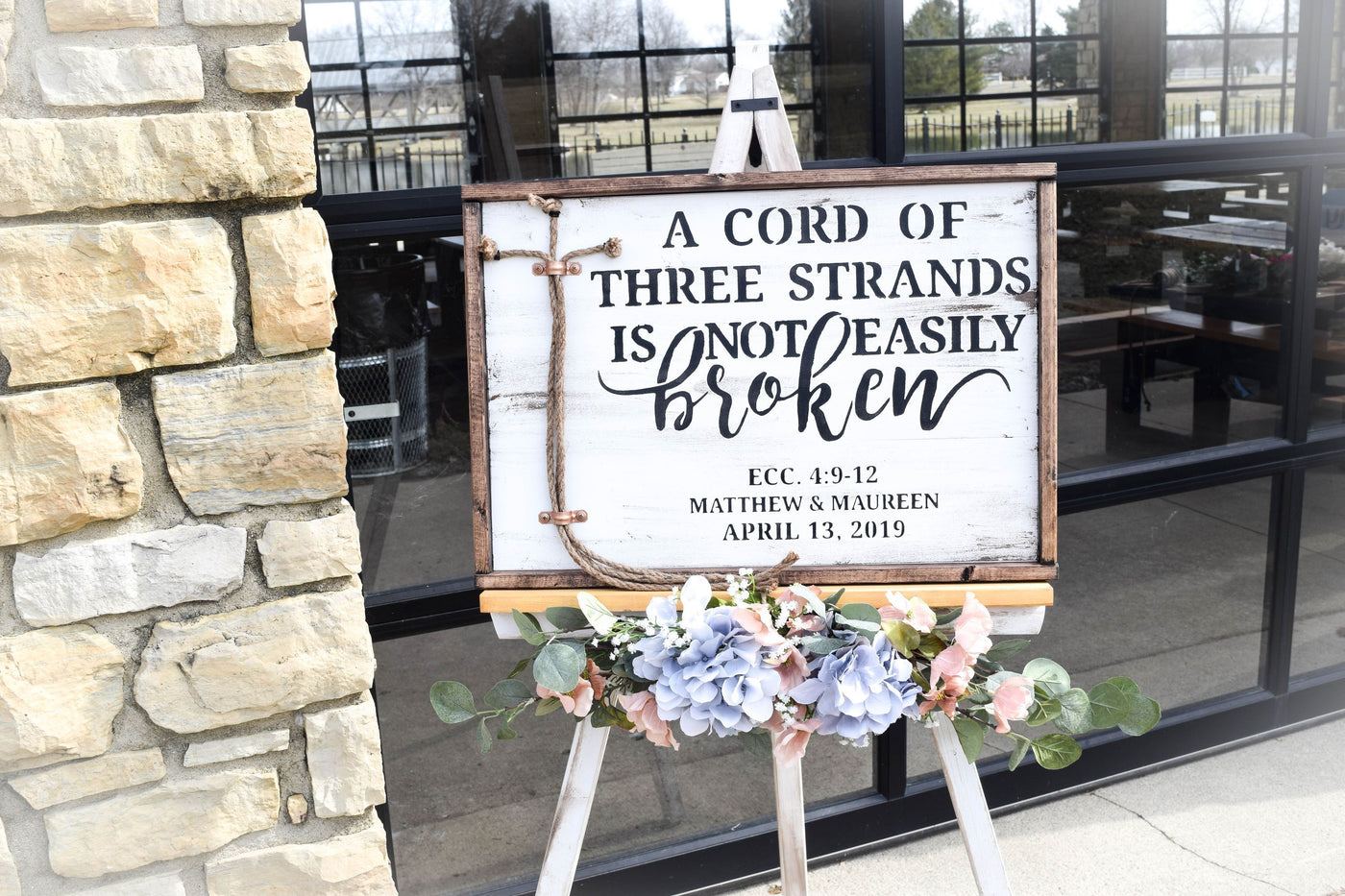 White unity ceremony sign with custom names on an easel for wedding